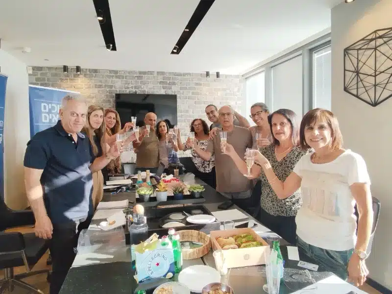 צוות קבוצת שמאי ויזמים בהרמת כוסית חגיגית במשרד לרגל פרויקט נדל"ן חדש בחולון.